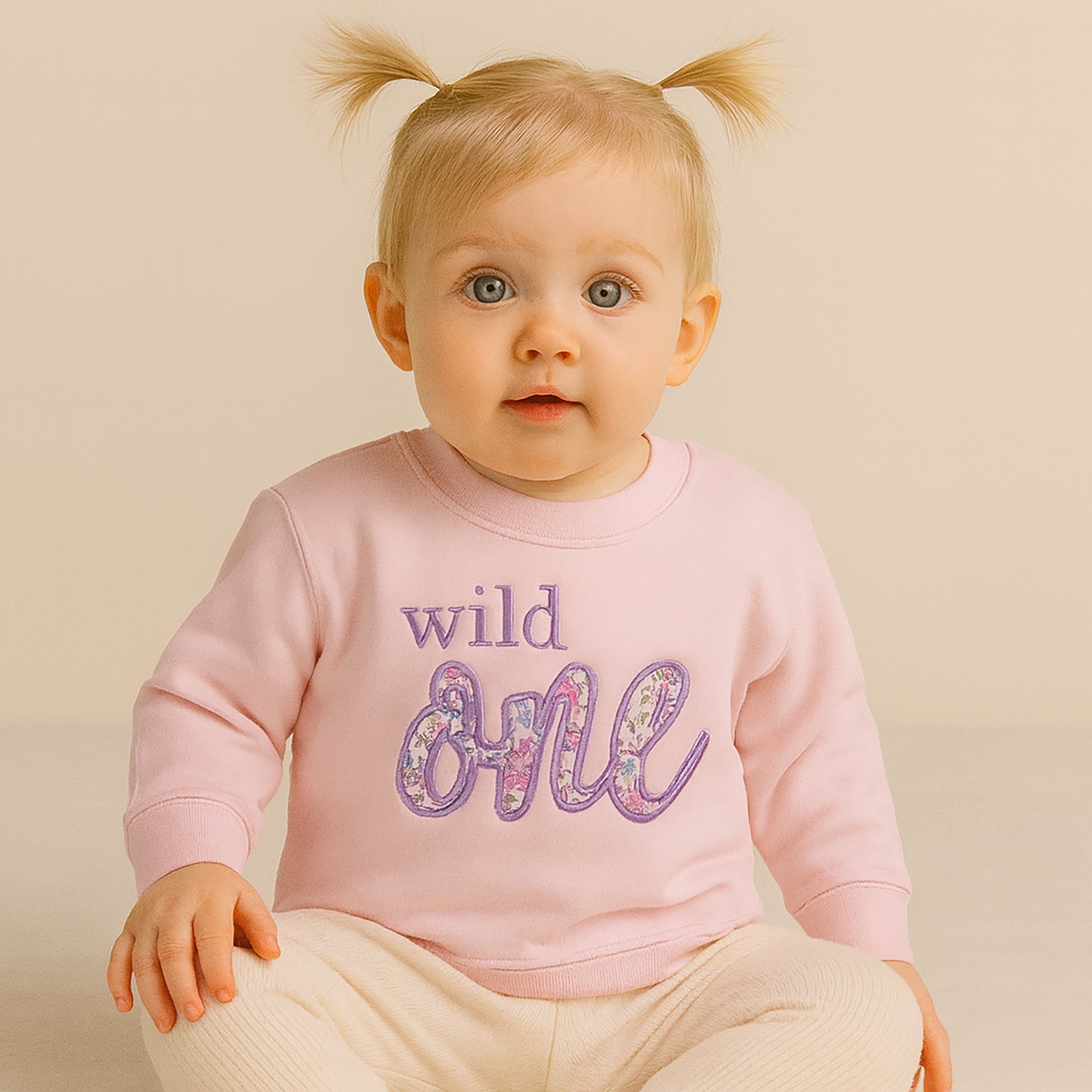 Toddler girl wearing personalised Wild One first birthday sweatshirt with Liberty of London ‘ONE’ applique UK