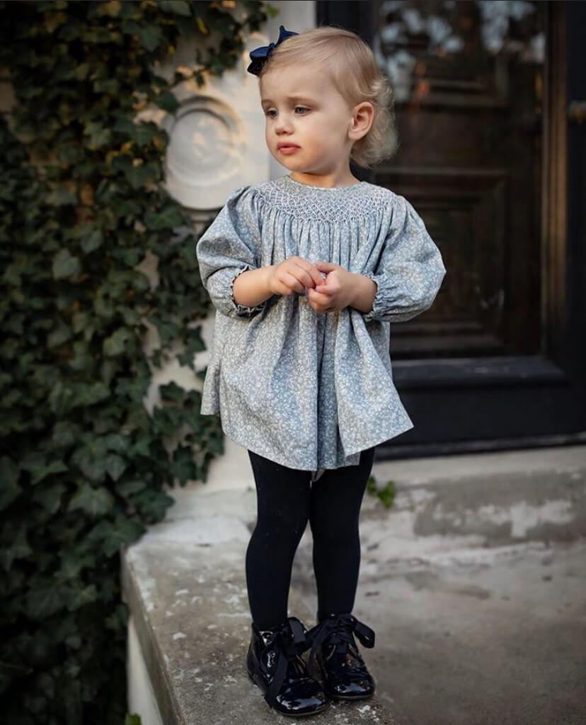 girl wearing spanish hand smocked baby outfit in blue