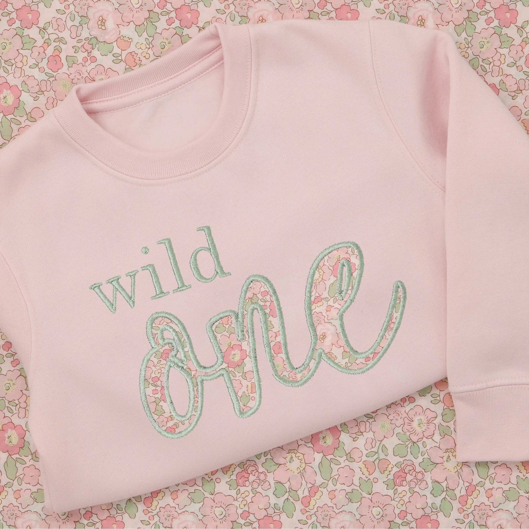 Personalised Wild One first birthday sweatshirt for girls UK – front view with custom name and Liberty of London ‘ONE’ applique
