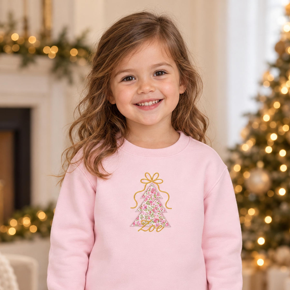 Girl wearing pink Liberty Christmas tree jumper with festive appliqué and gold name embroidery.