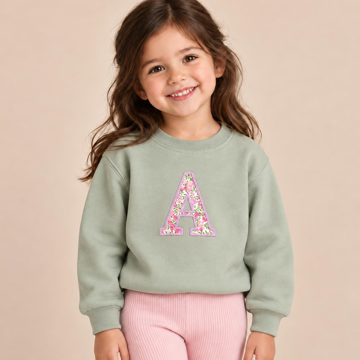 Girl wearing sage personalised initial jumper with Liberty fabric letter appliqué