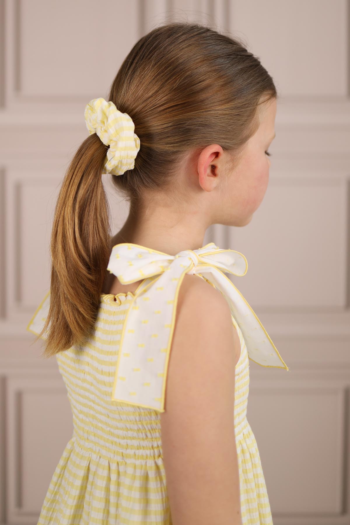 model wearing yellow striped sun dress with scrunchie